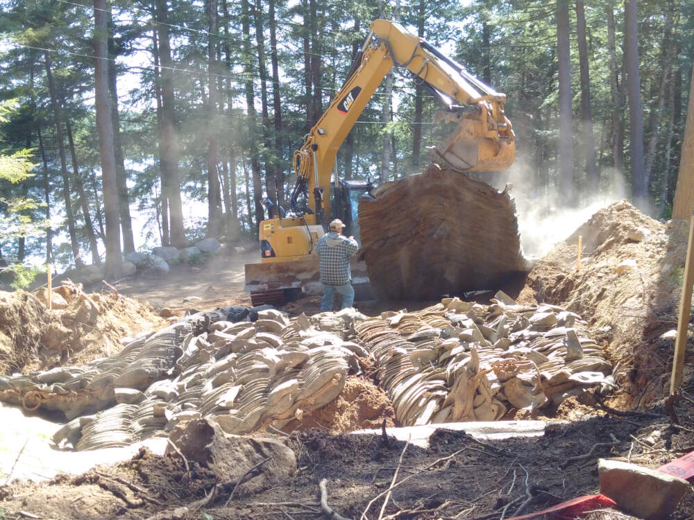 An excavation contractor lifts protective mats used in explosive rock removal and bedrock blasting on Muskoka construction project.