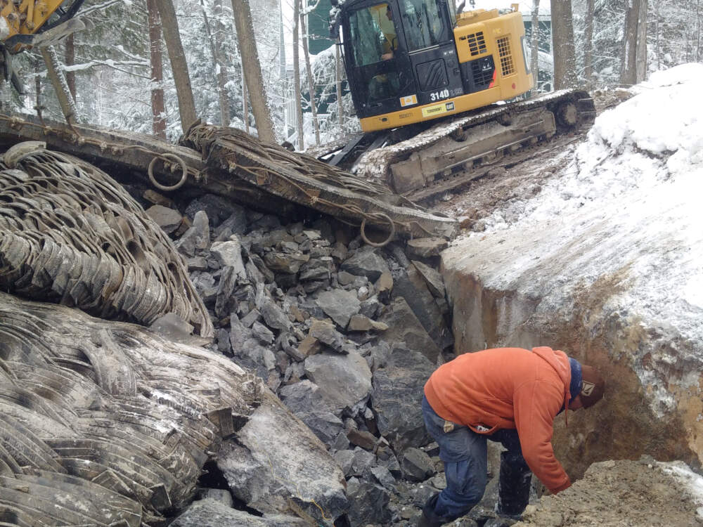 Drilling, blasting and excavating work with rubber blast mats, drilling contractor and excavation contractor personnel in view.