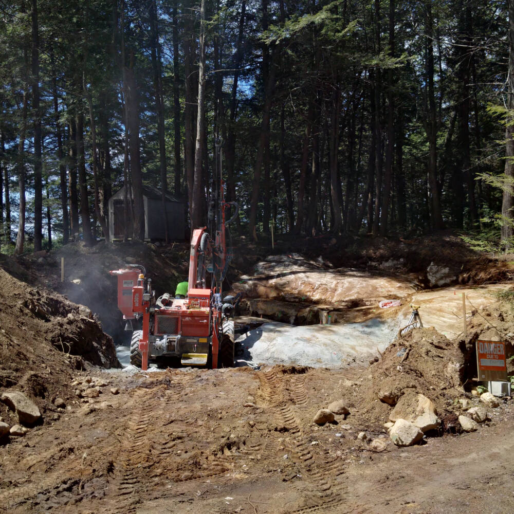 Excavation, drilling and blasting are underway during site preparation of a sunny building site nestled into dense forest surroundings in Township of Lake of Bays, Muskoka, Ontario.