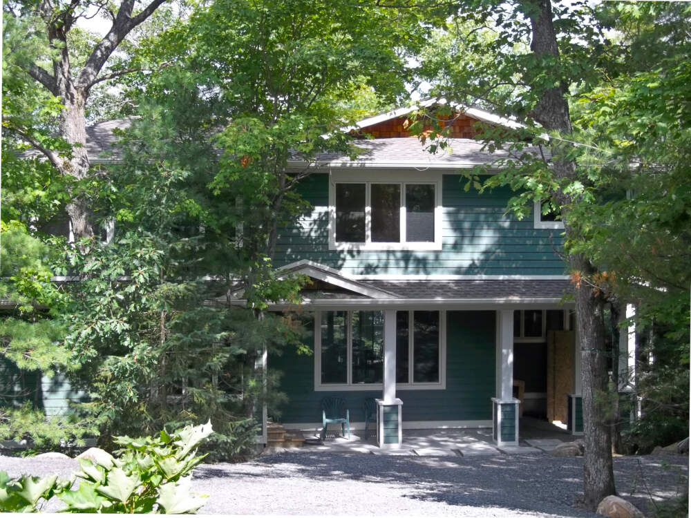A large cottage on Leonard Lake peeks out between mature trees on the building site near Bracebridge in Muskoka, Ontario.