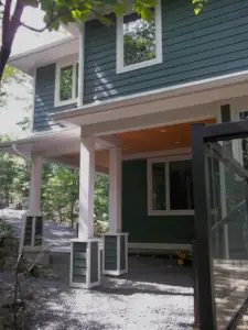 The upper floor footprint overhangs the lower floor footprint, thereby allowing exterior circulation to connect the driveway to the waterfront access path.