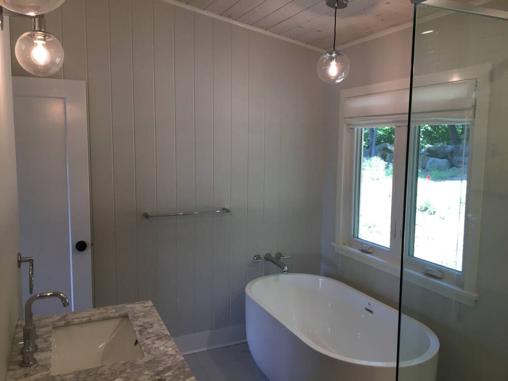 A luxurious bathing tub, ceramic tile floor and marble vanity countertop with decorative lighting in a Muskoka builder's construction project.