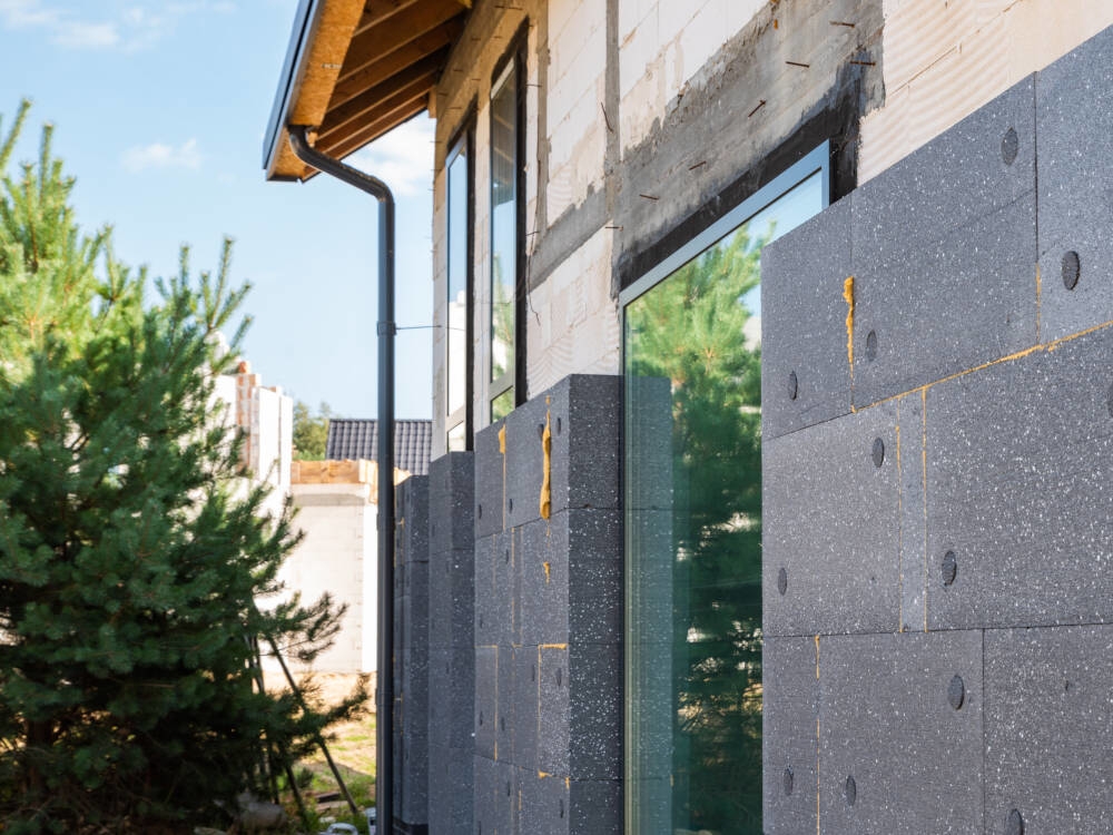 A thick layer of extruded polystyrene insulation forms a continuous thermal barrier at the exterior face of the walls of an energy-efficient home or Certified Passive House construction project.