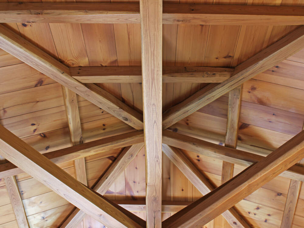 Intricate geometry and hand-cut joinery frame a wooden vaulted ceiling in a timber frame home.