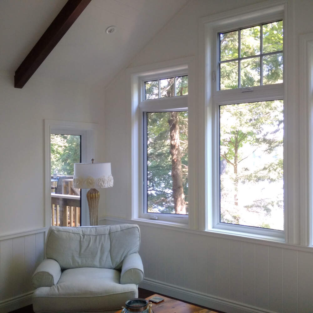 Coniferous trees visible through the lakeside windows in a cottage interior on MacKay Lake near Bracebridge, Muskoka, Ontario.