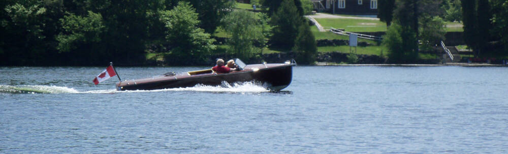 A well-maintained antique wooden boat shines in the sun while travelling across Lake Joseph near Port Sandfield, Muskoka, Ontario.