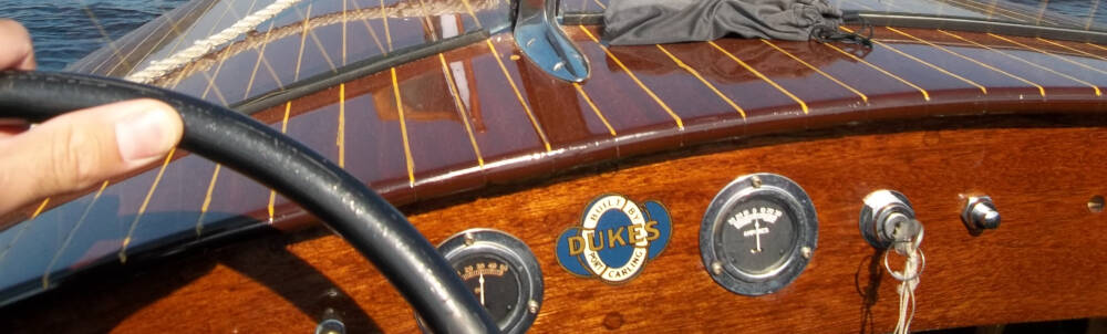 Hand on the steering wheel of a classic wooden boat on the lake in Muskoka.